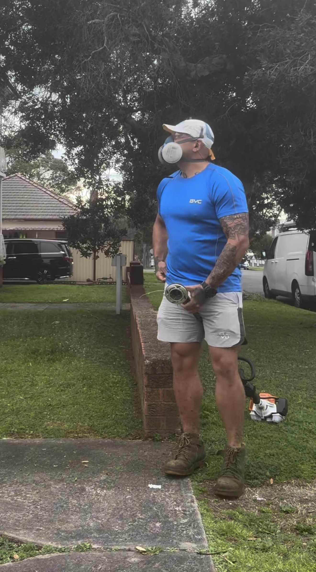 BVC crew member in a blue BVC shirt and respirator holding a line trimmer